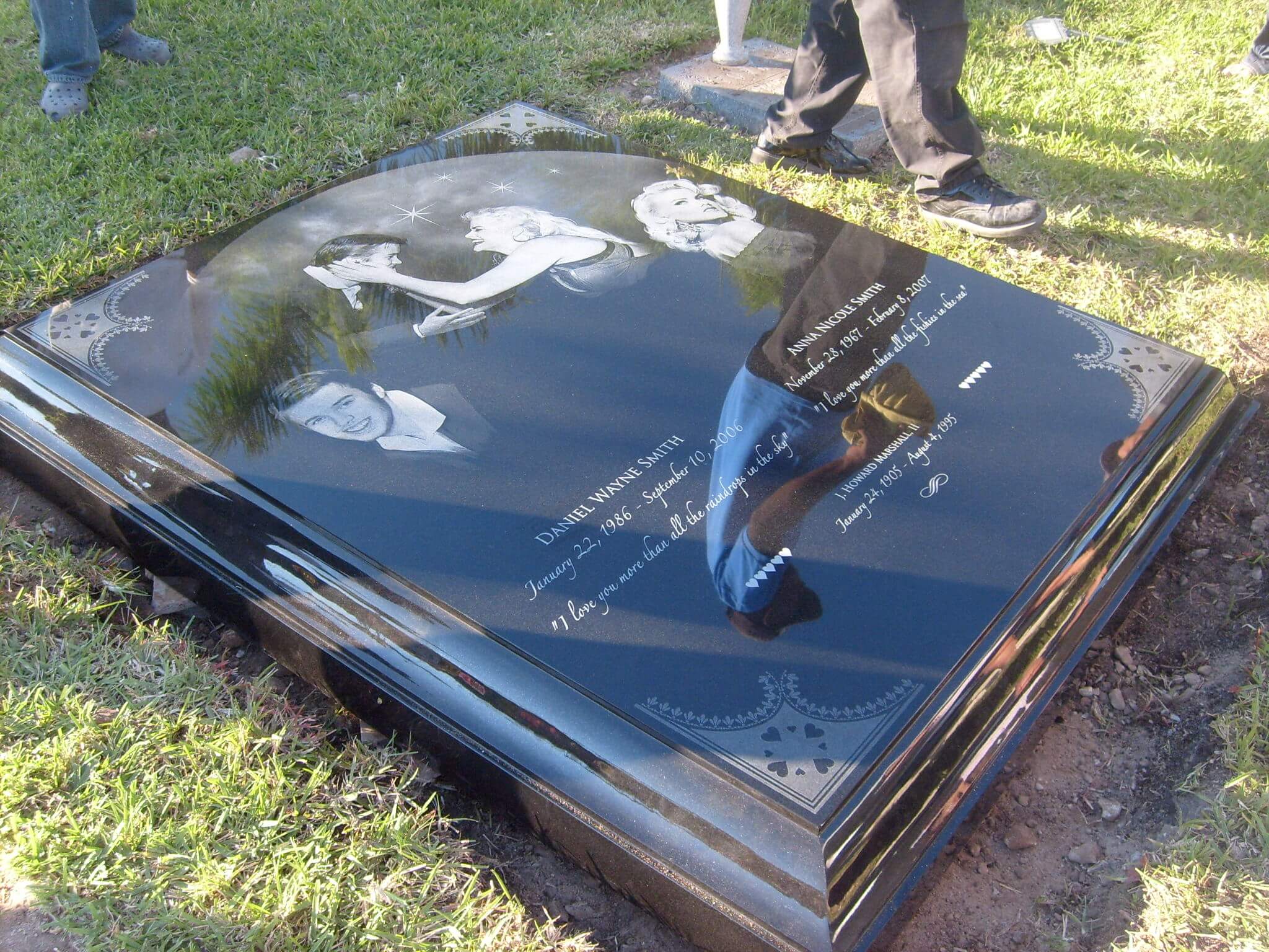 Large polished black granite ledger monument with laser etched portraits, being set in the ground