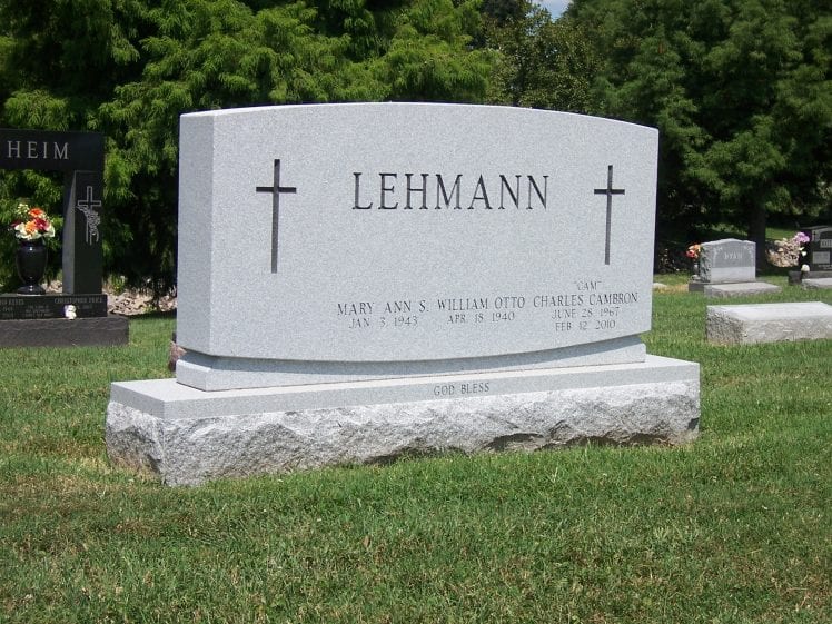 Grey granite traditional upright monument with carved crosses on a rock-pitched base